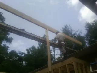 Carpenter setting a ridge beam over a new addition frame — Ice Dam Removal by Roofing Brothers in Brisbane