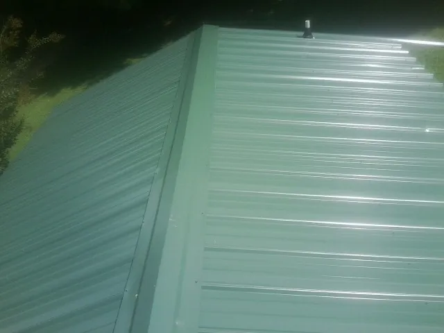 New green metal panels meeting at the ridge of a roof — Flat Roof Repair work by our crew in Brisbane