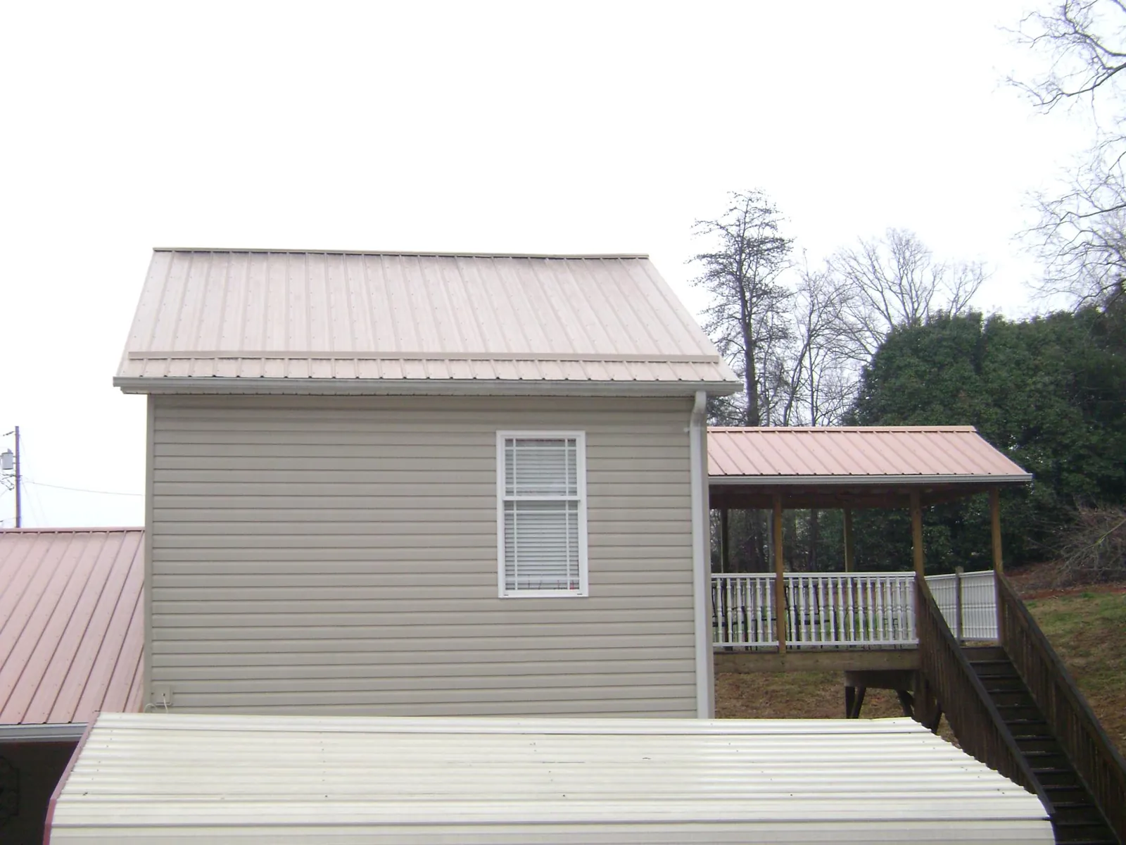 Tan metal roofs on a two story addition and attached porch, from a Roof Replacement job in Brisbane